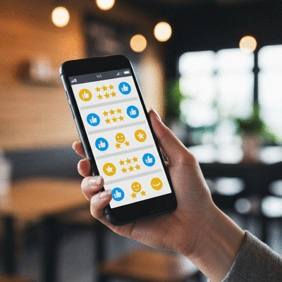 Closeup of a hand holding a smartphone displaying positive online reviews, set against a blurred background of a modern office or cafe